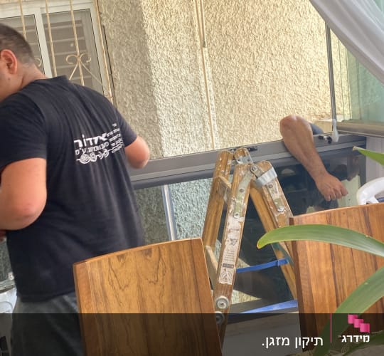 התקנת מזגן על ידי טכנאי ליד חלון פתוח